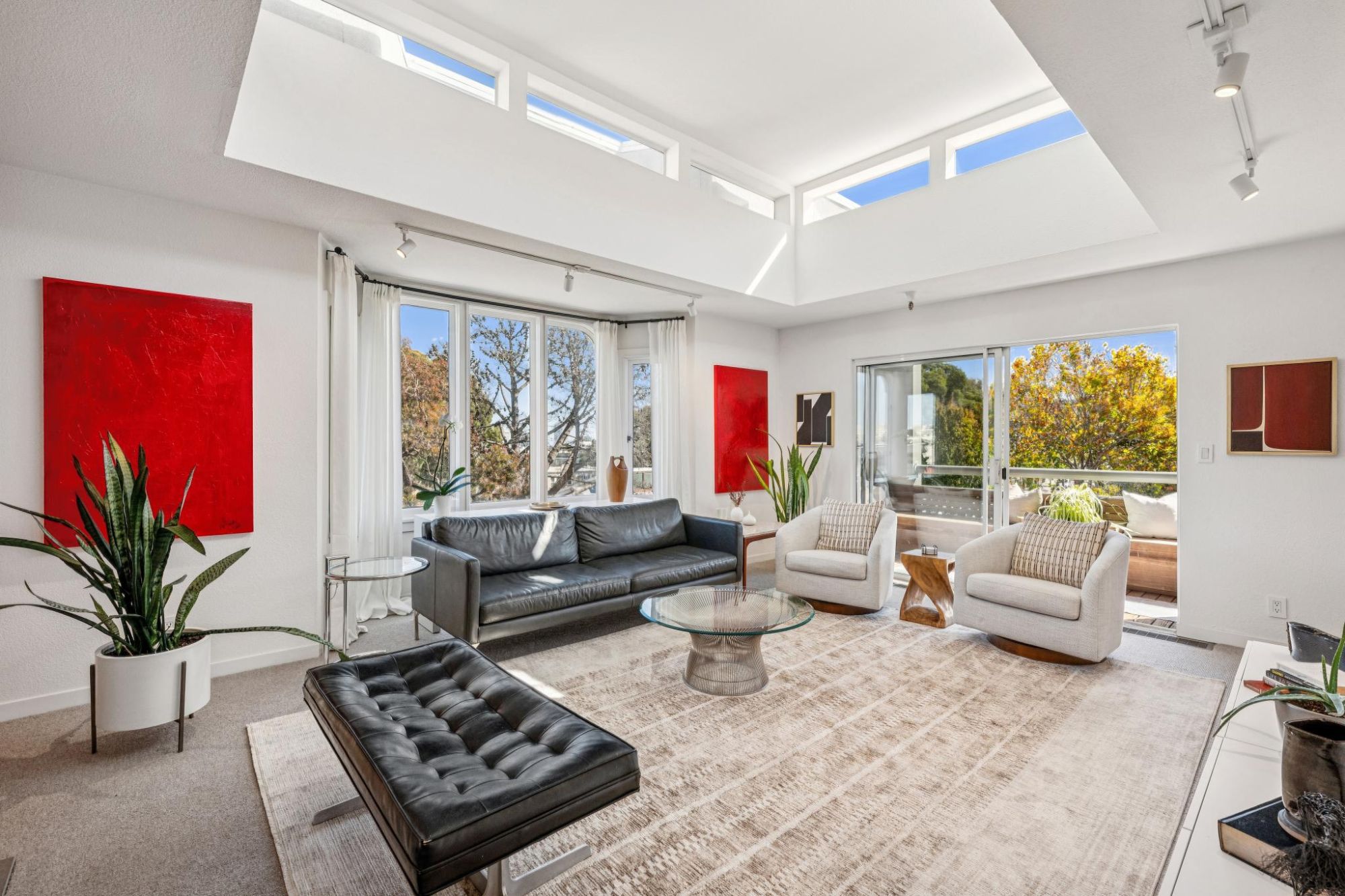 Living room with clerestory windows, curved bay window and sliding door to the balcony