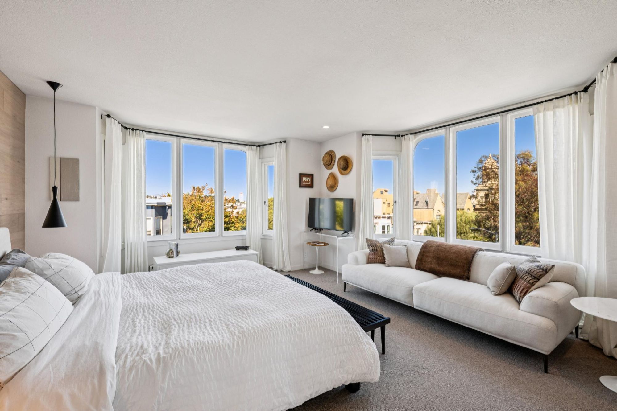 Primary bedroom with sofa, bed and bay windows